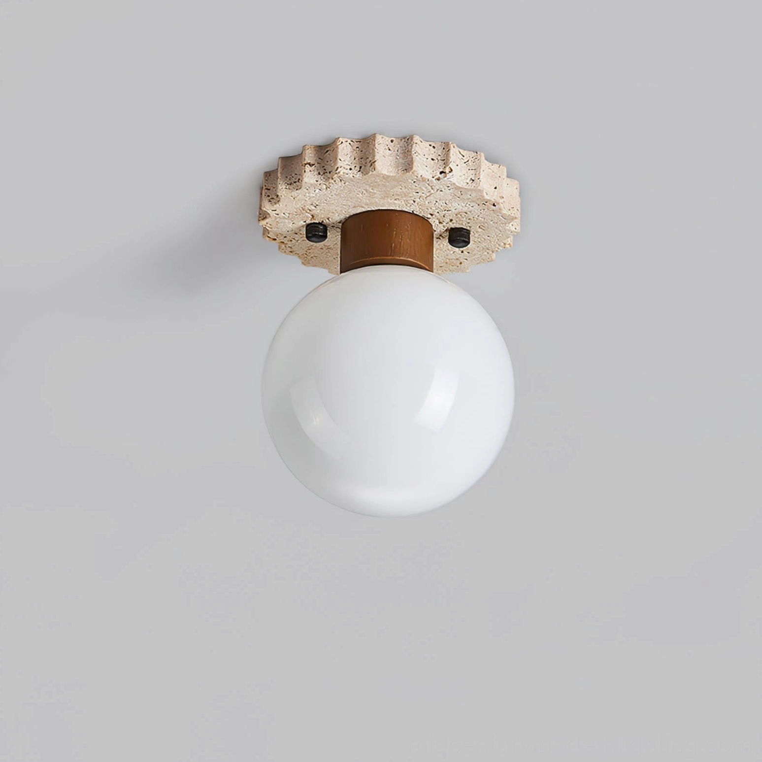 Overhead front view of spherical ceiling lamp with serrated porous travertine mounting base and white glass shade detail