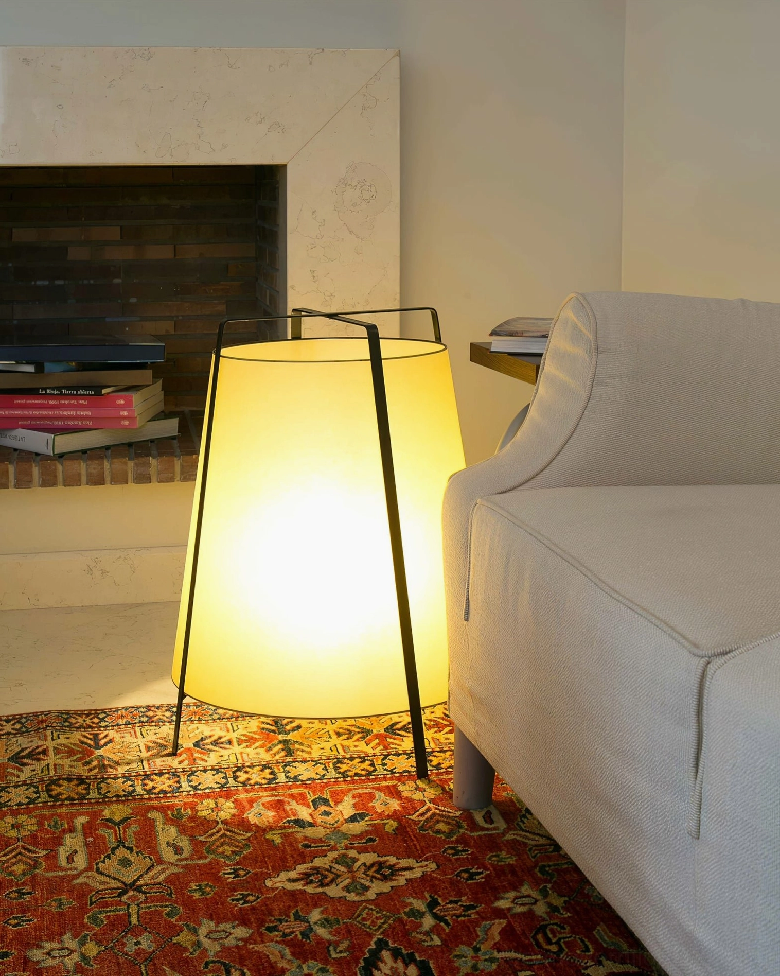 Akane table lamp in modern minimalist living room setting near fireplace and sofa, three-quarter front perspective