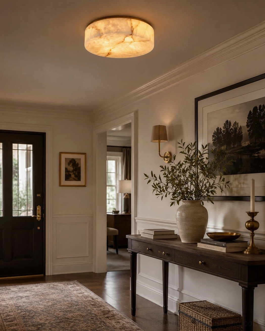 Low-profile alabaster flush mount light installed in hallway with white wainscoting and dark wooden doors