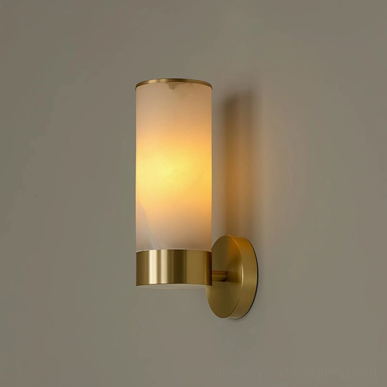 Contemporary alabaster wall sconce side angle showing brass hardware, cylindrical stone shade, and warm light emission on neutral background
