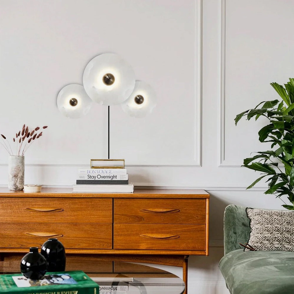 Multi-lamp alabaster sconce displayed beside mid-century modern dark wood dresser accent piece
