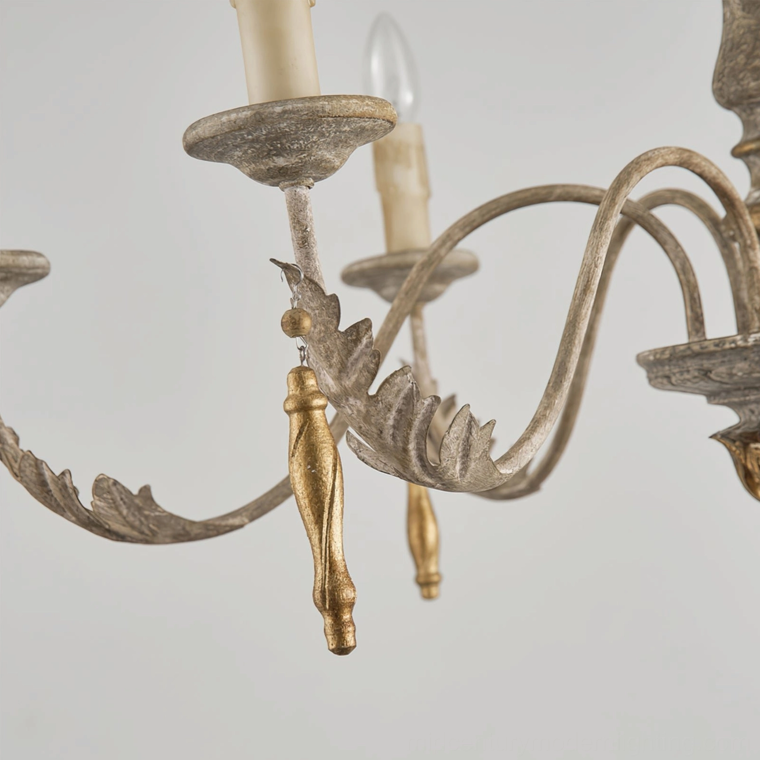 Alda chandelier arm detail showing ornate leaf-carved metal design with gold drop pendants