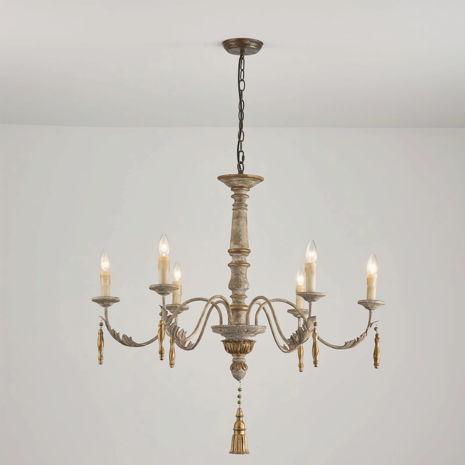 Alda chandelier illuminated in minimalist interior, low-angle view showing warm candlelight and tassel drop details