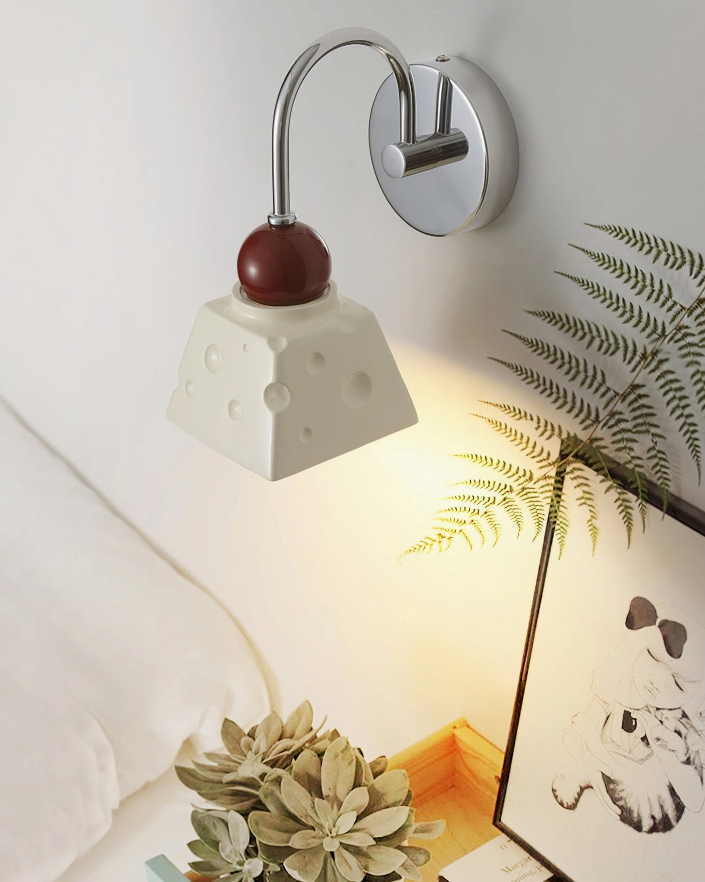Alma bedroom wall sconce close-up bedside with green plants and framed wall art display