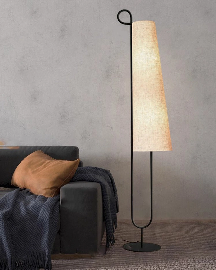 Ancora floor lamp providing ambient light in living room corner with dark grey fabric sofa, throw blanket and cushions