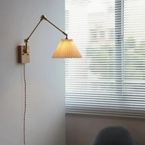 Angeline plug-in wall lamp installed in minimalist bedroom, warm brass tones and walnut wood, indoor side angle perspective