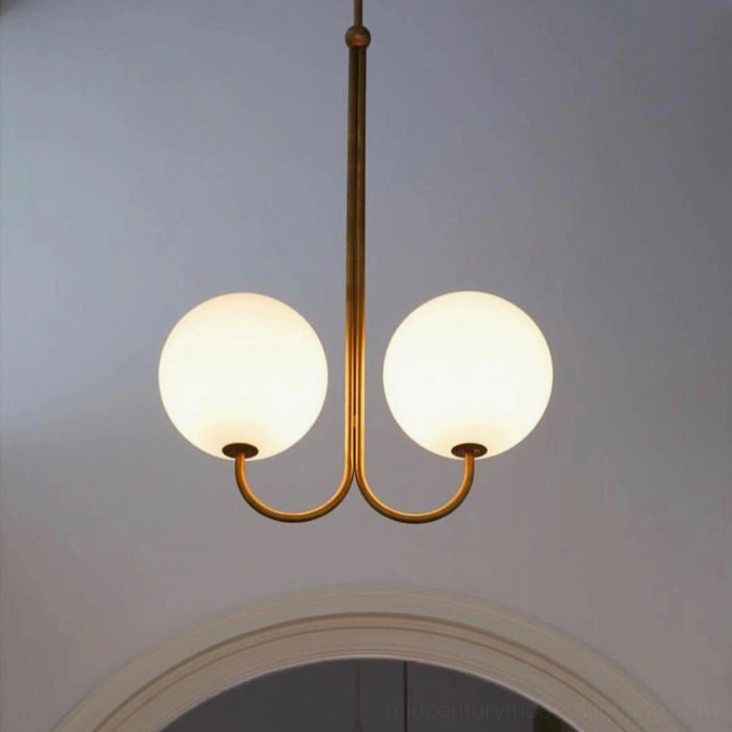 2-head angle chandelier with curved brass frame and warm-glowing frosted glass shades in modern interior space