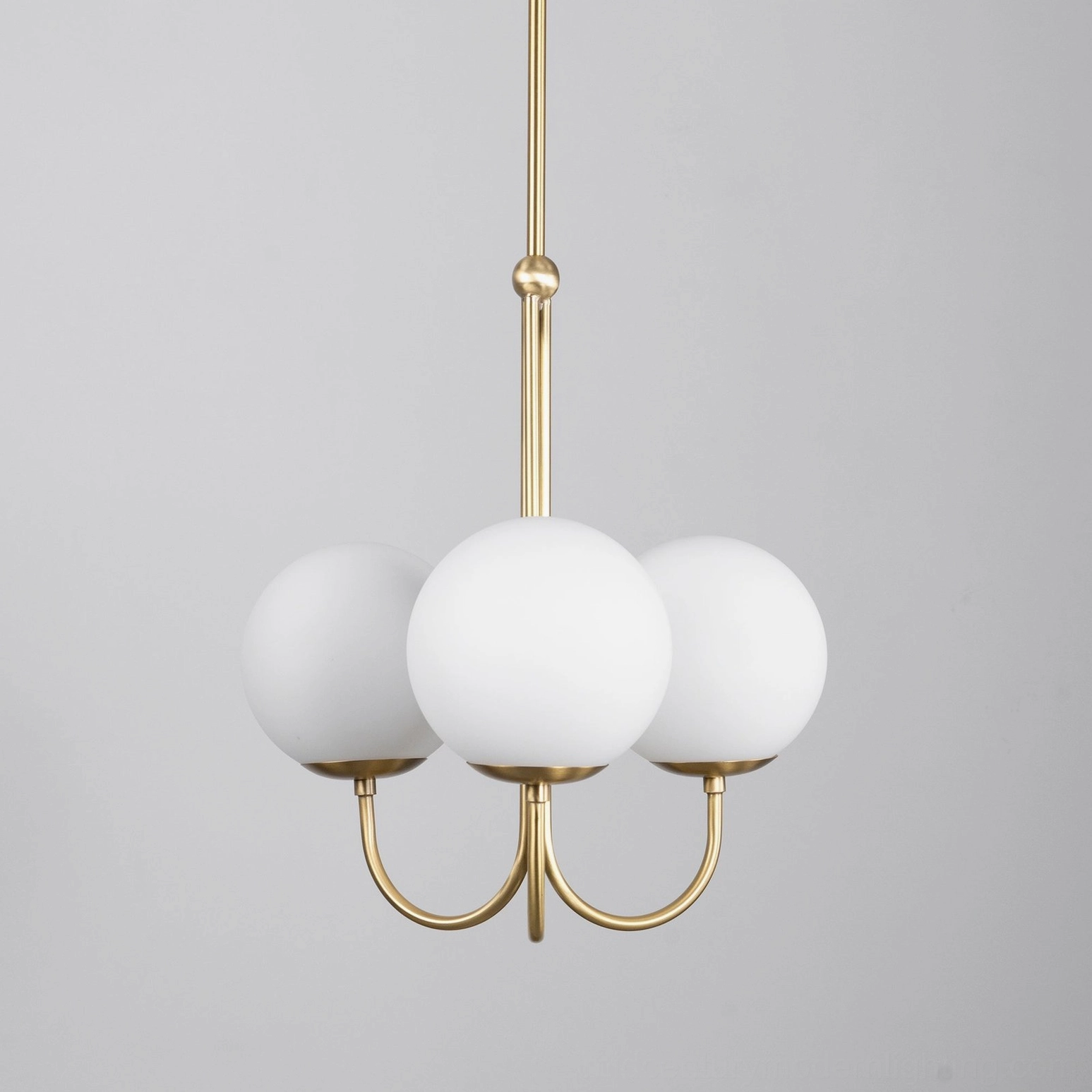 Close-up front view of 3-head angle chandelier showing curved brass arms and frosted glass globe details