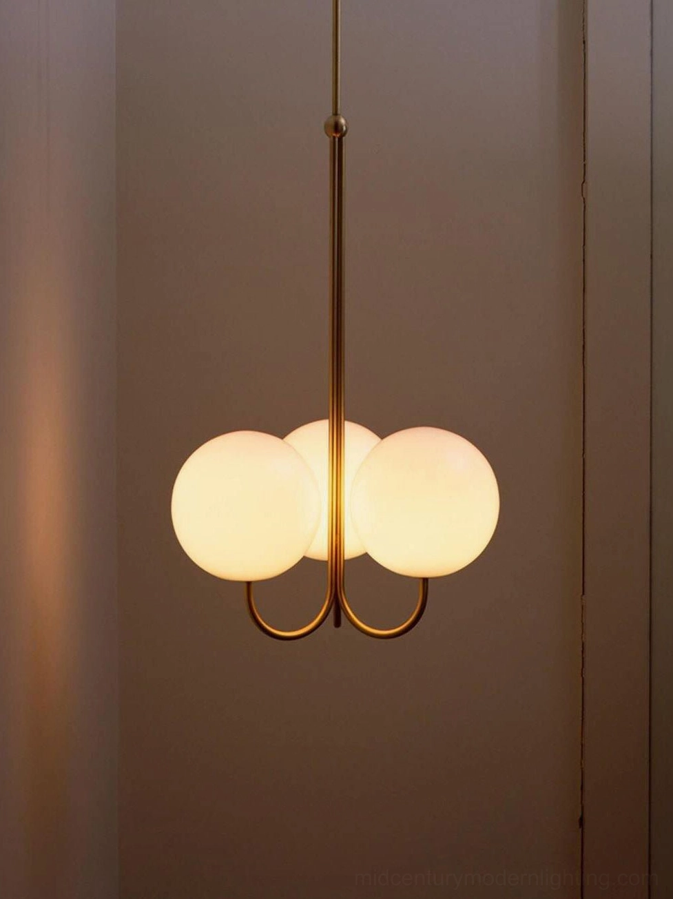 3-head frosted glass globe chandelier with illuminated brass frame in neutral hallway interior