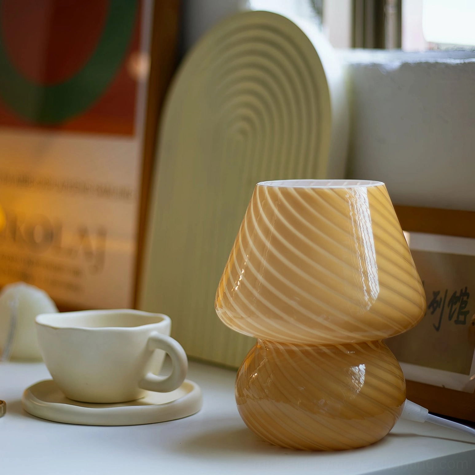 Brown spiral ribbed Ansel mushroom table lamp on tabletop art display with retro art backdrop