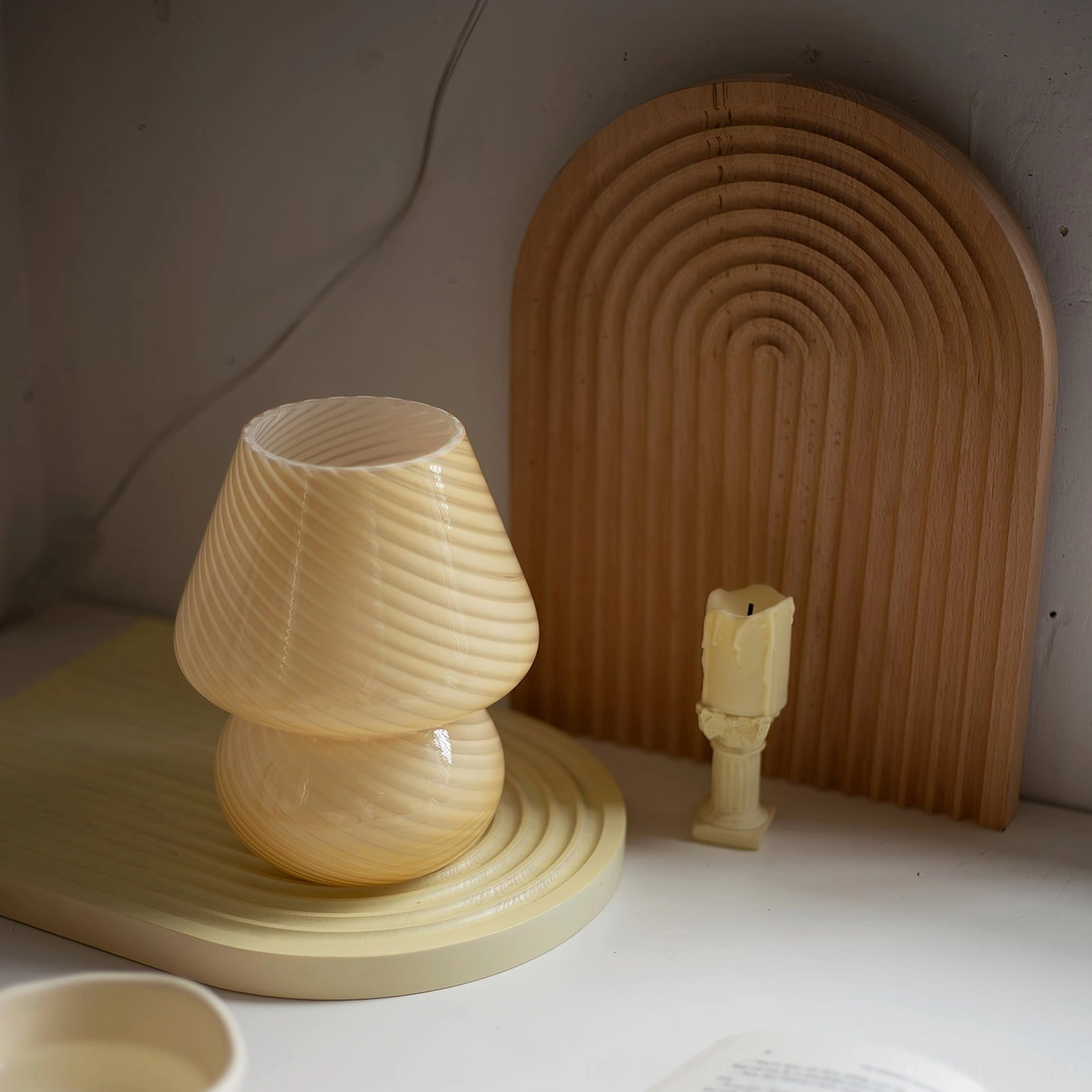 Unlit Ansel mushroom glass lamp with cream beige spiral texture on minimalist tabletop with wooden coaster
