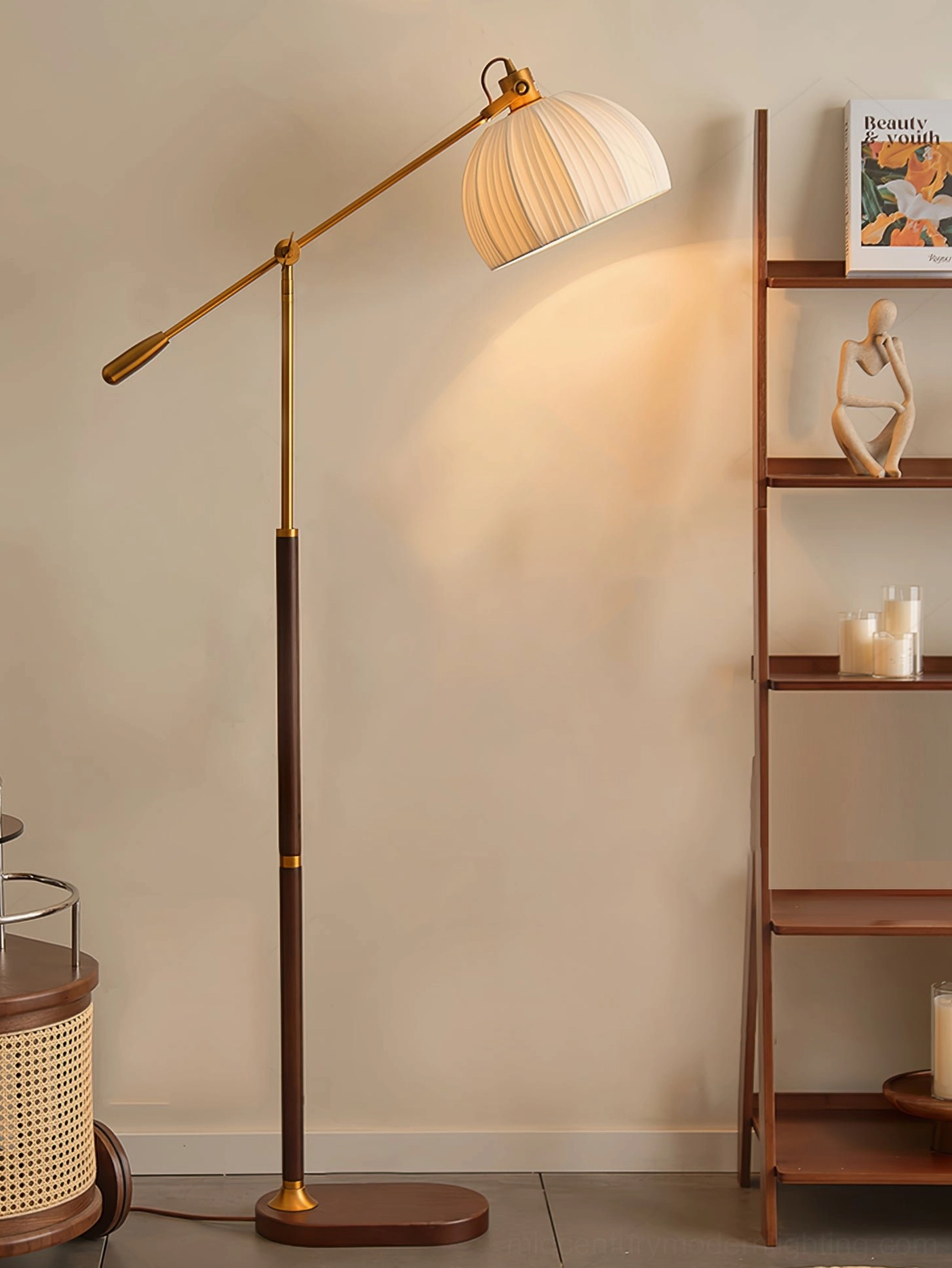Adjustable pleated fabric floor lamp with dark walnut pole and brass hardware details, off-white shade in front of wooden display shelf