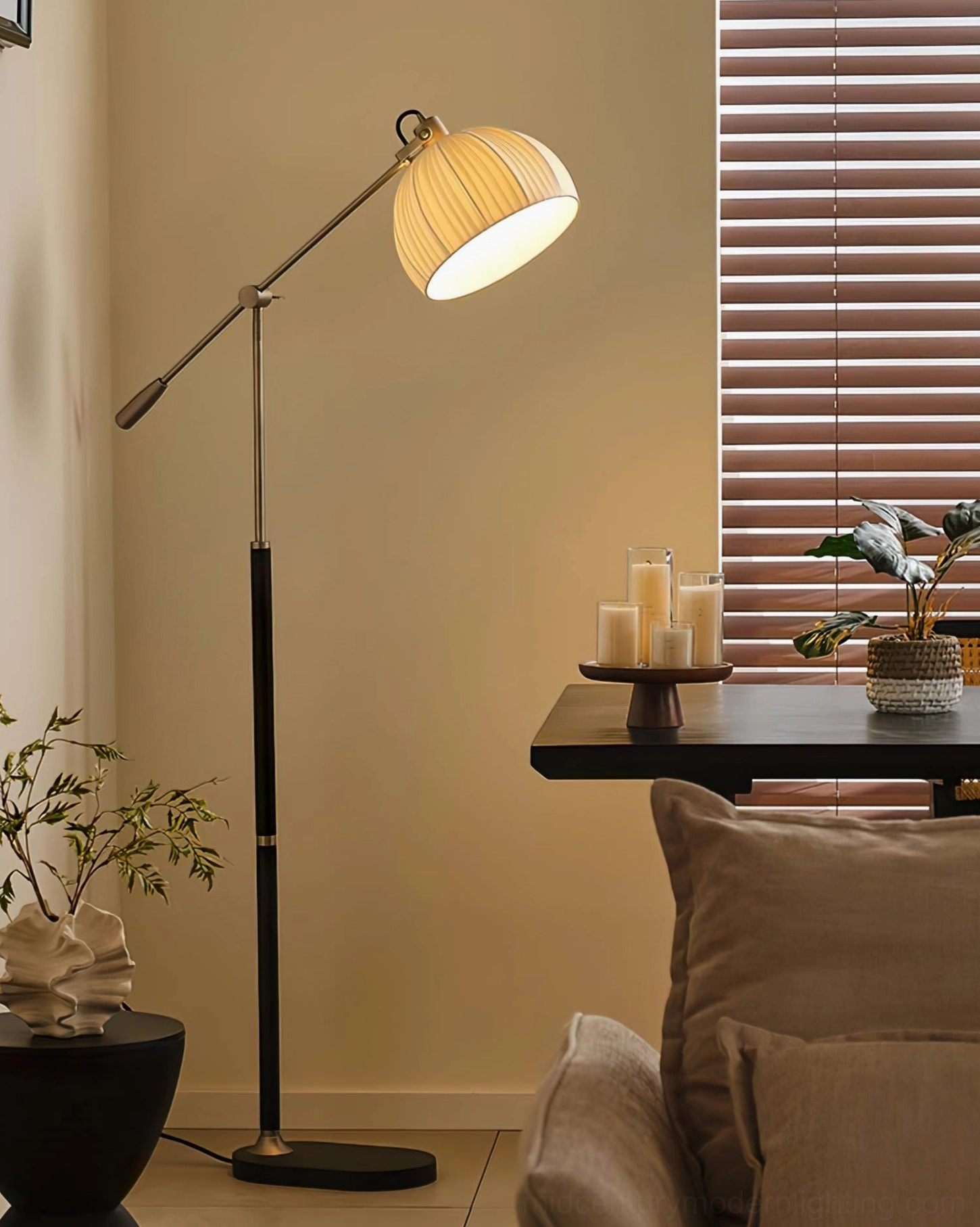 Adjustable swing arm floor lamp with black metal pole and brass lamp head accent in side table corner setting with warm neutral home decor