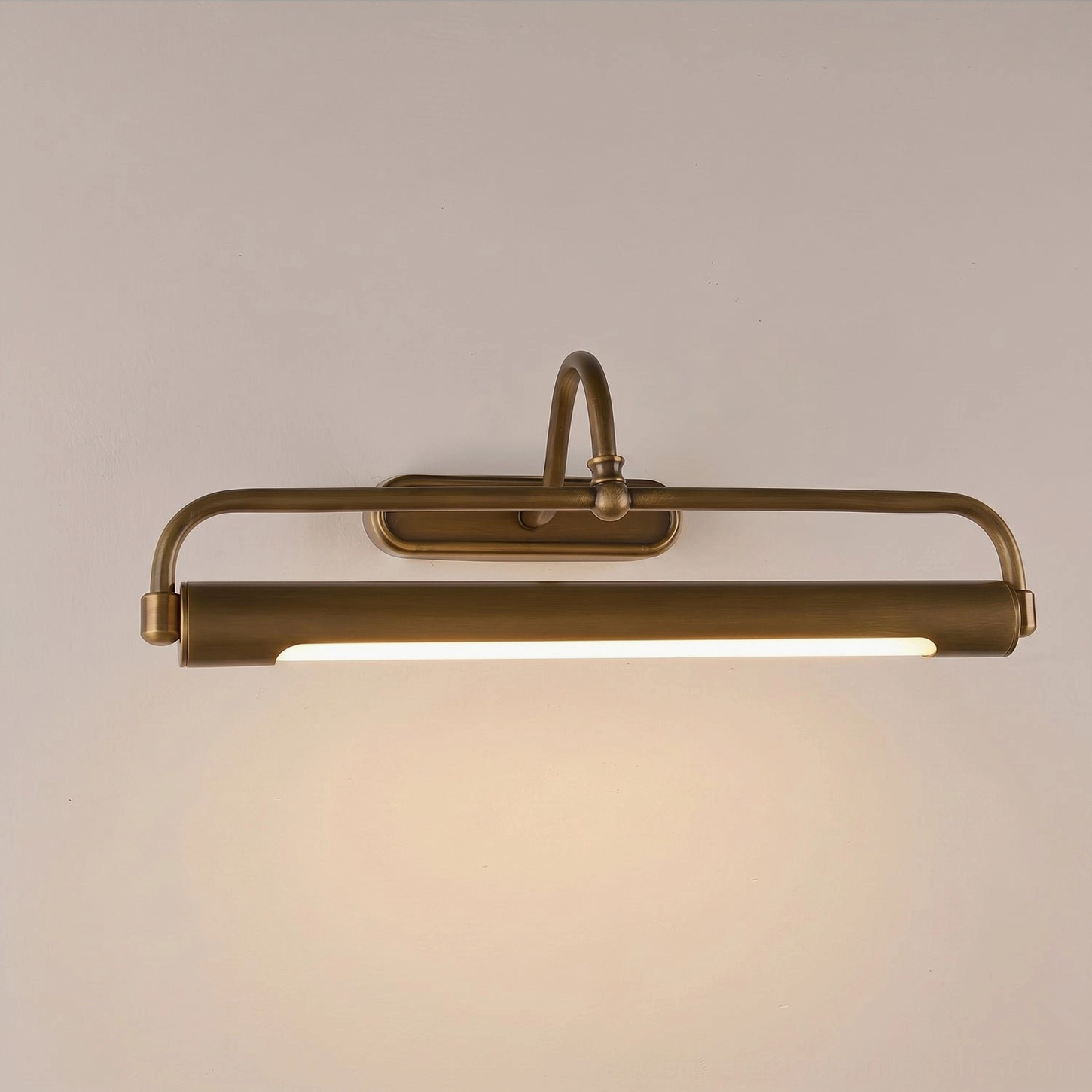 Antique brass wall sconce with graceful curved arm, warm light accent over bookshelf