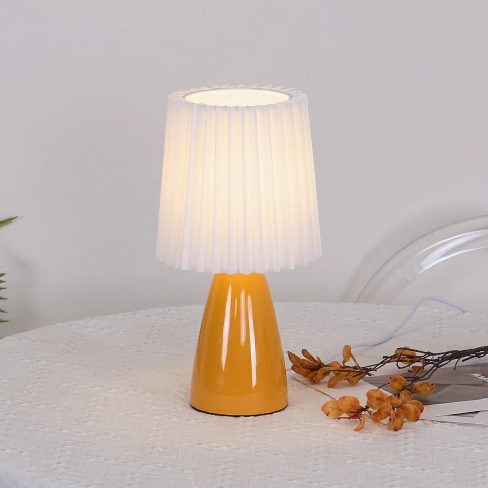 Apollo pleated table lamp lit on dining table with dried flower decor, warm ambient light