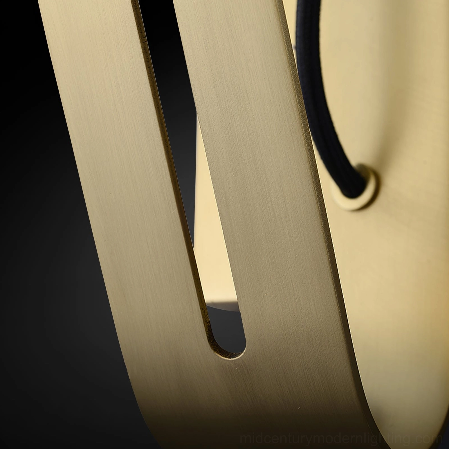 Close-up macro view of brushed brass Arandela arm with slotted design and metal texture