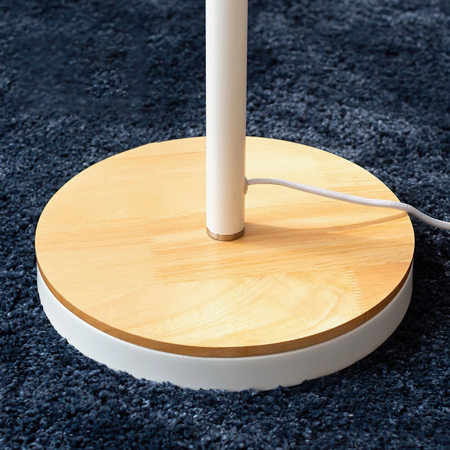 Arc floor lamp base and pole featuring wooden foot and metal stand on textured carpet