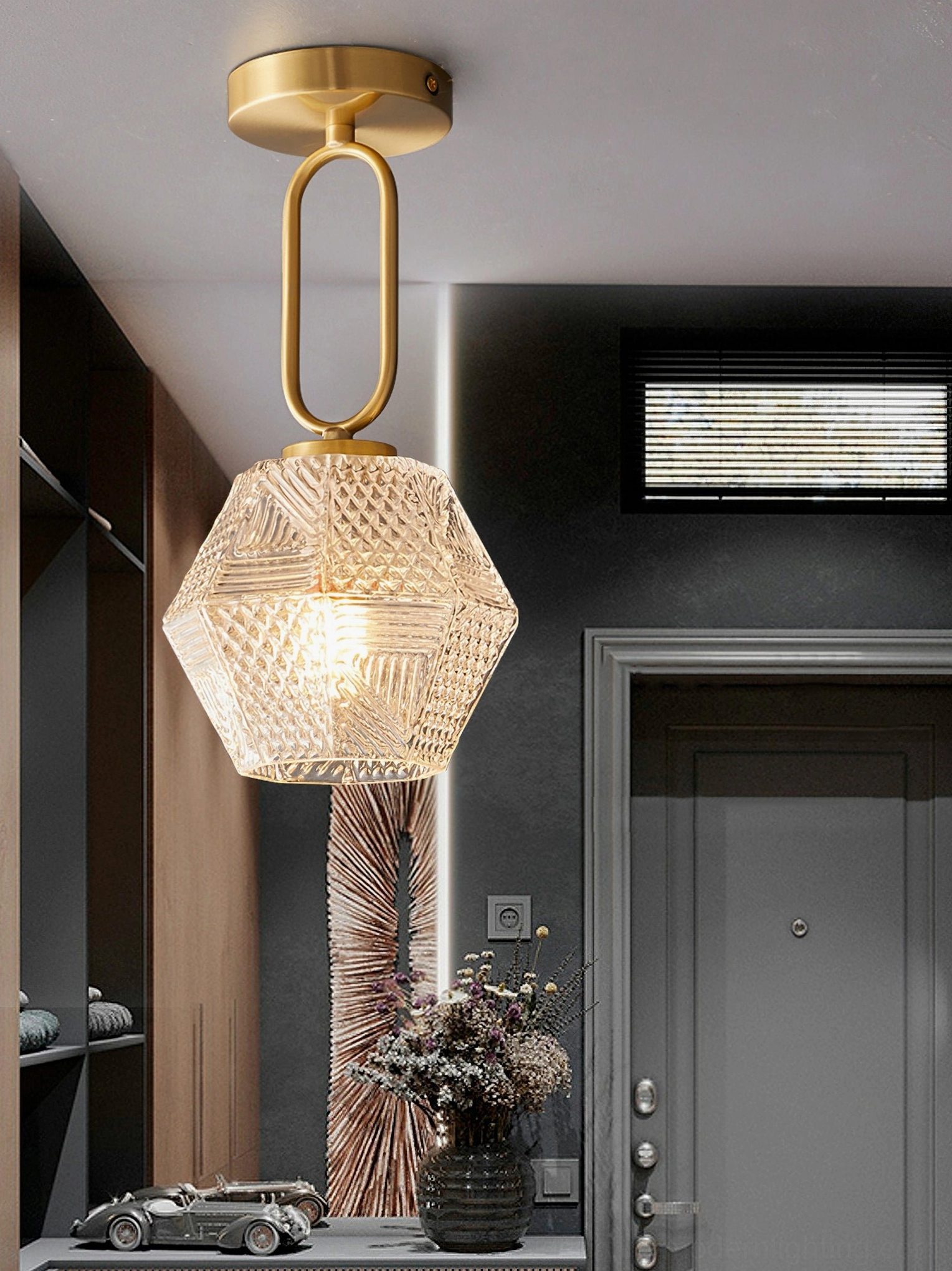 Art Deco pendant ceiling light with long brass suspension arm and faceted glass shade entryway