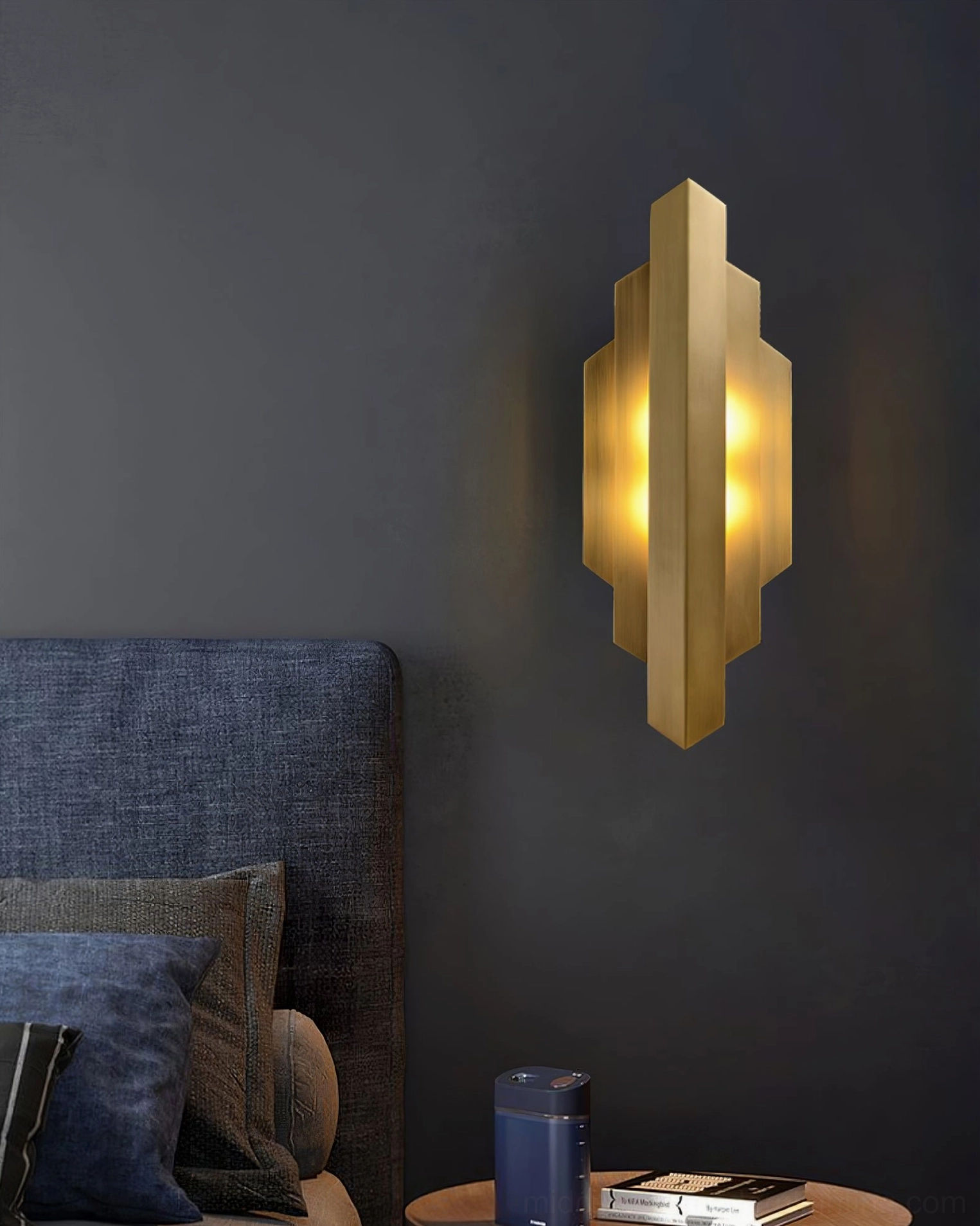 Art Deco brass wall sconce in modern bedroom with navy blue upholstered headboard and warm lighting