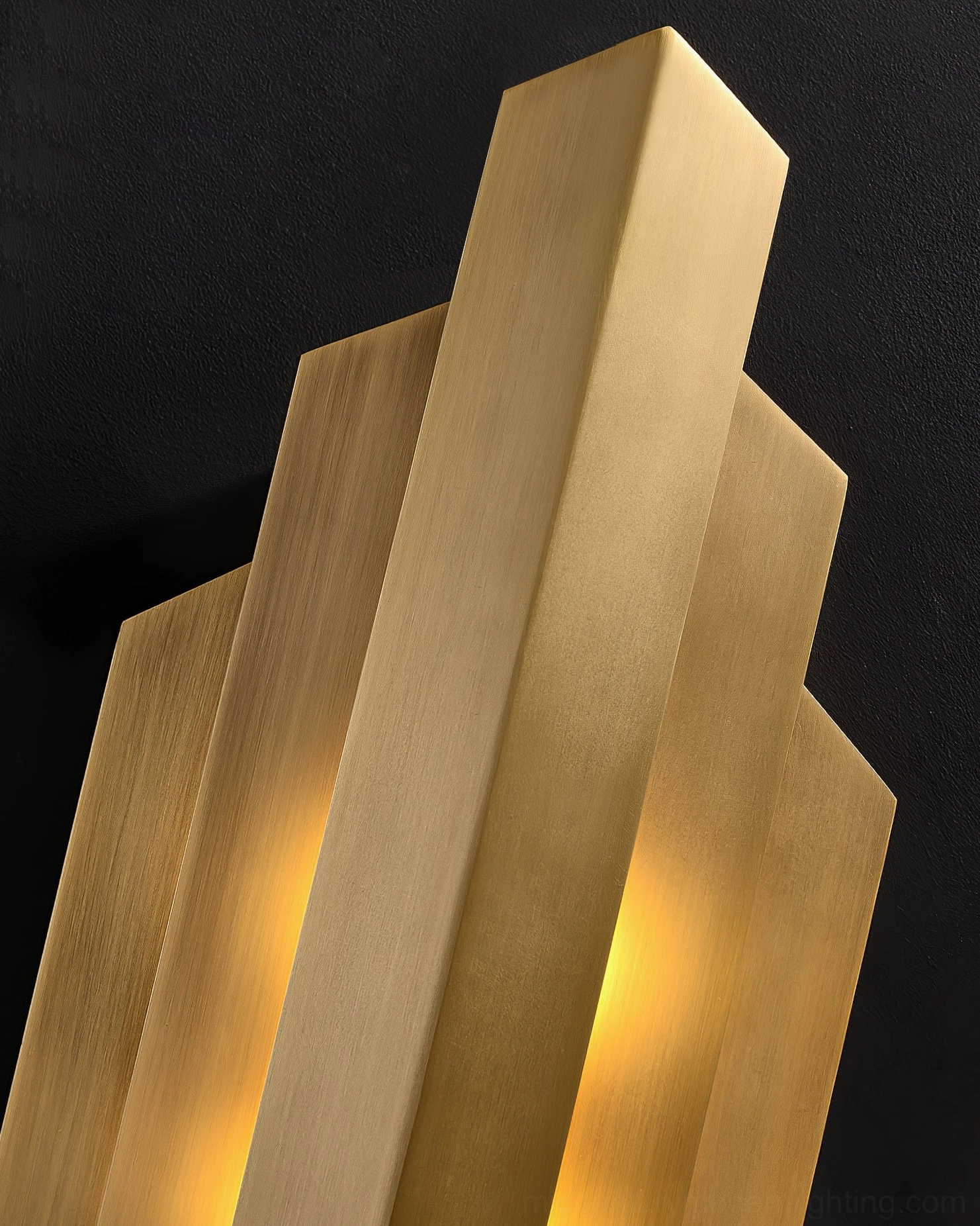 Side perspective close-up of Art Deco brass sconce highlighting stepped metal construction and warm glow