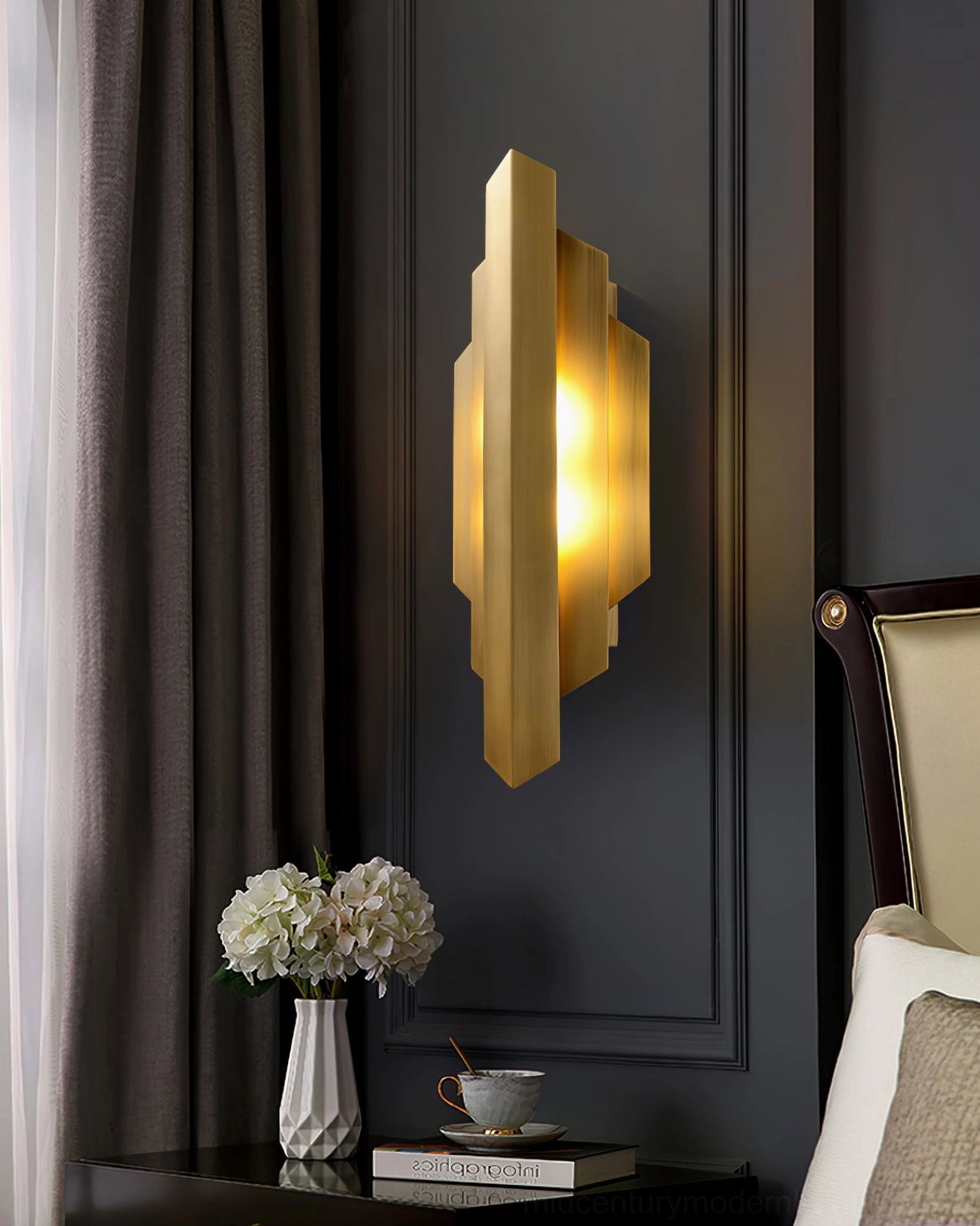 Single polished brass Art Deco sconce installed in modern bedroom vanity area with dresser and mirror