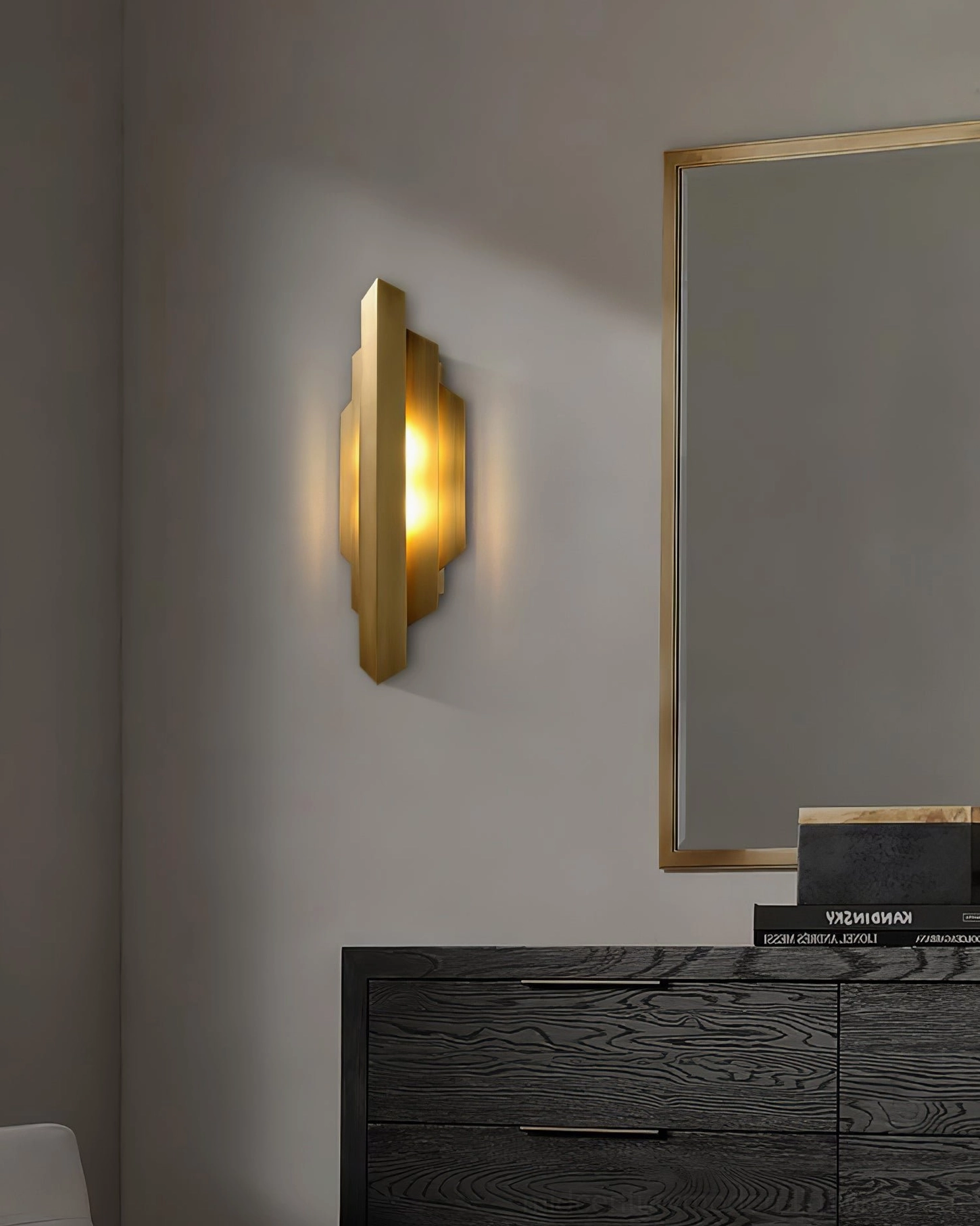 Brushed brass Art Deco wall lamp positioned beside bedroom vanity with dark wood furniture