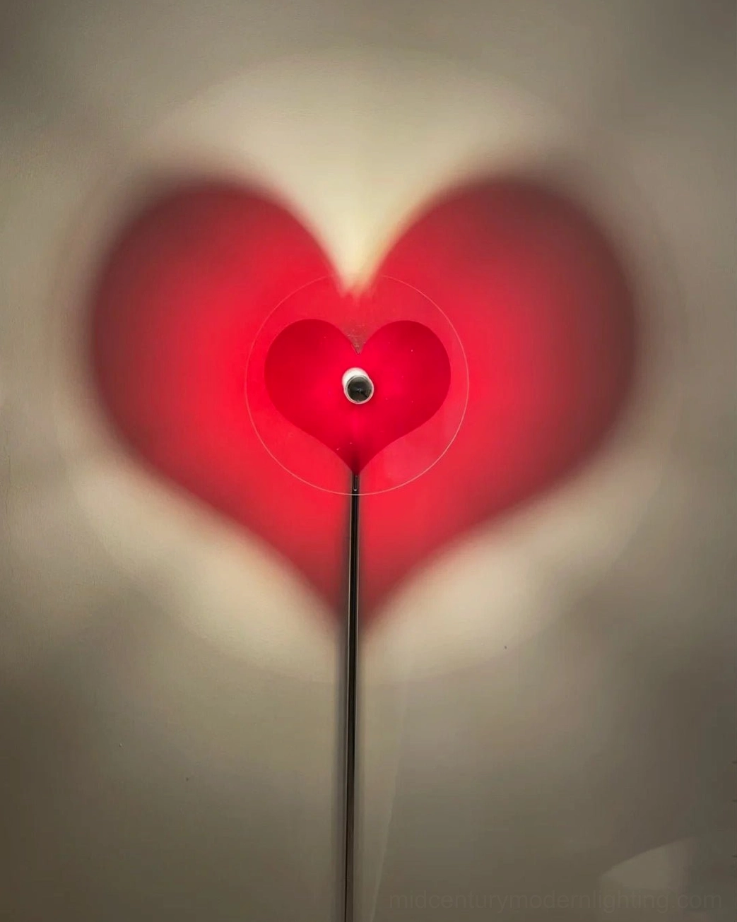 Modern heart-shaped floor lamp creating artistic light projection on wall for bedroom or living space