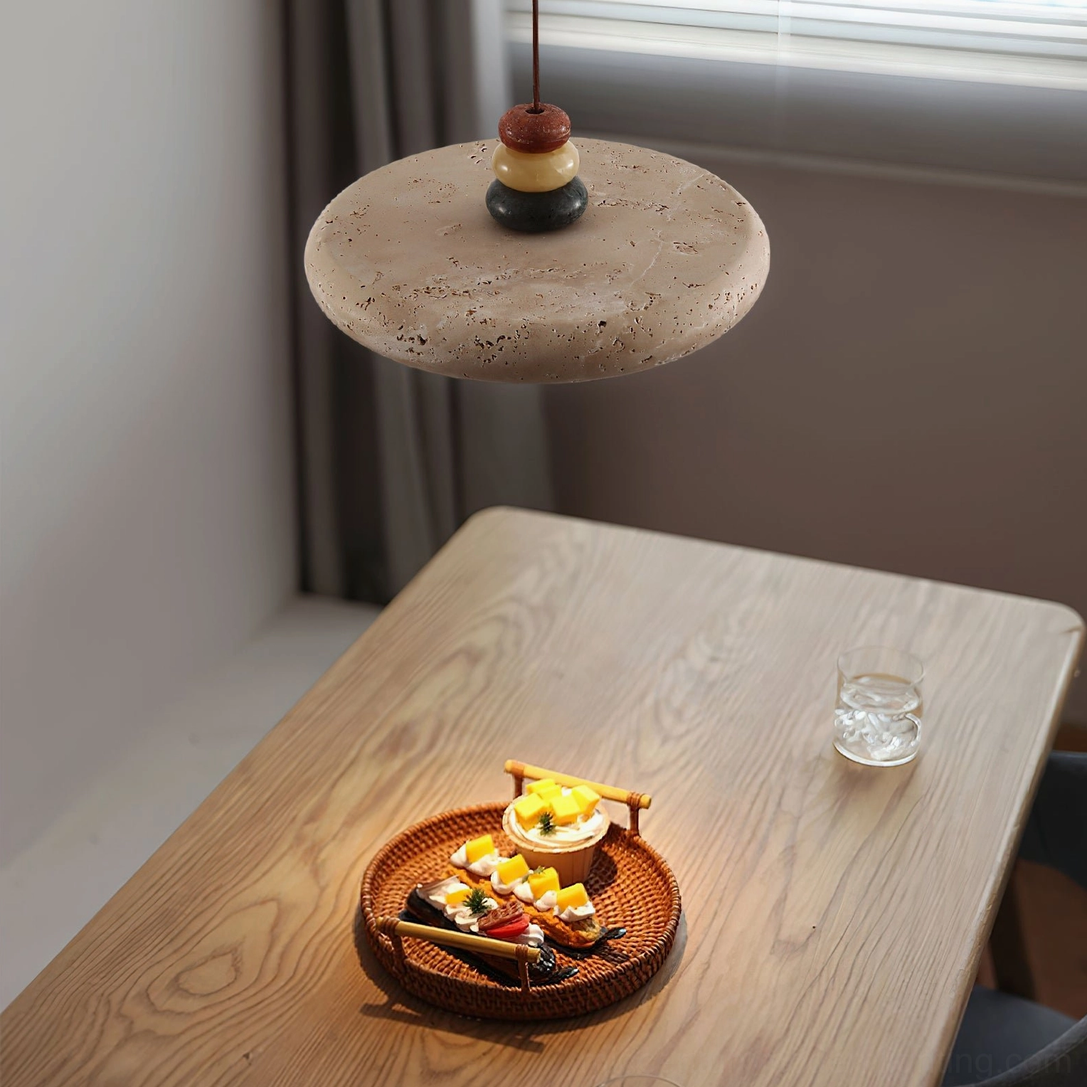 Sculptural travertine pendant with black finial base above casual dining area - overhead side angle