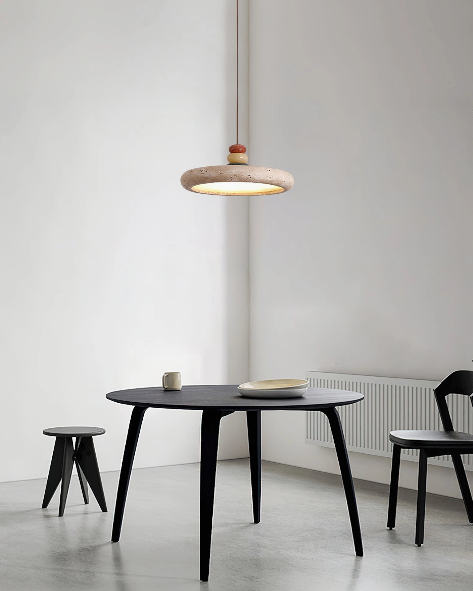 Travertine stone pendant light in small apartment dining space with black minimalist furniture
