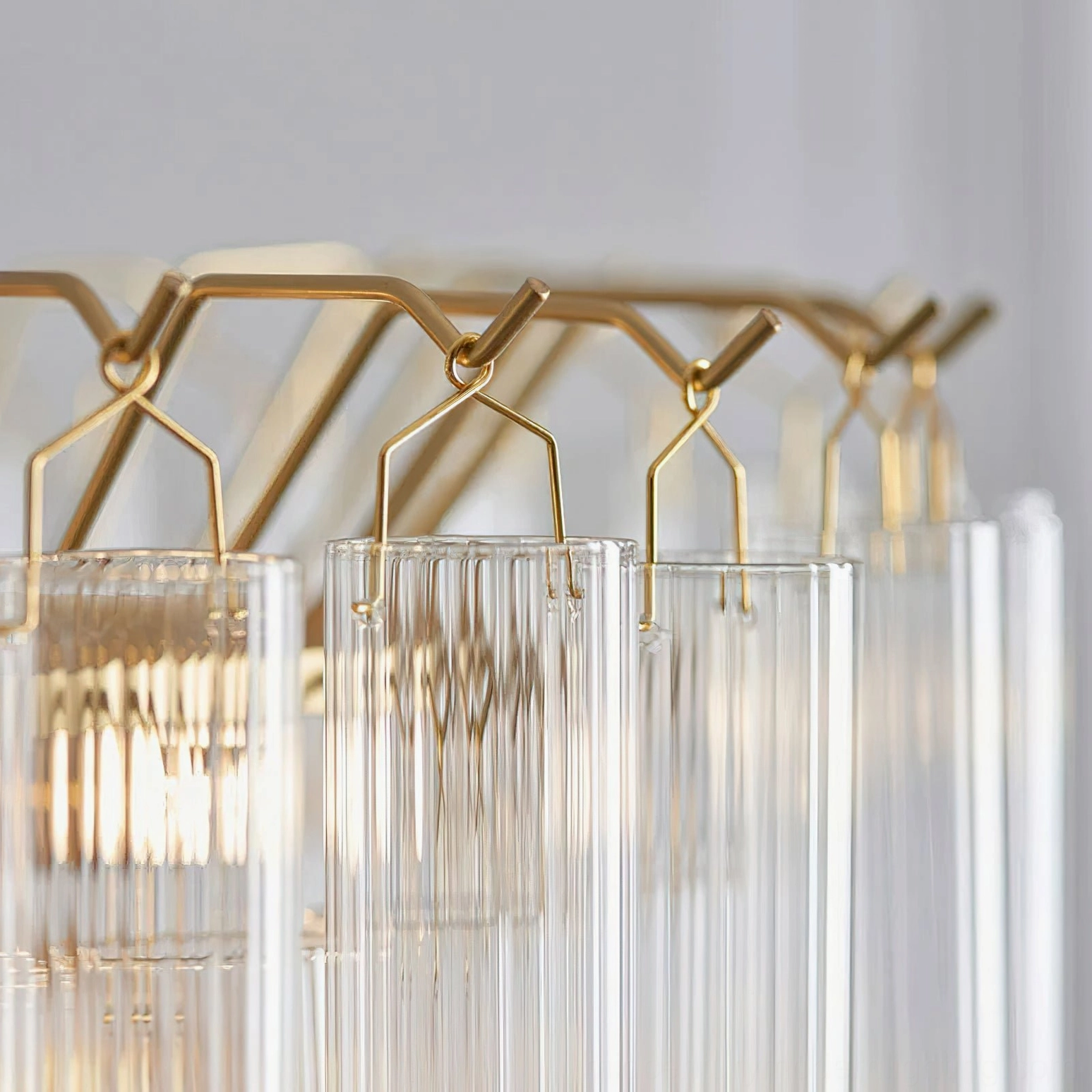Astoria Waterfall Glass Chandelier hardware - low-angle close-up of brass brackets and suspended crystalline glass cylinders