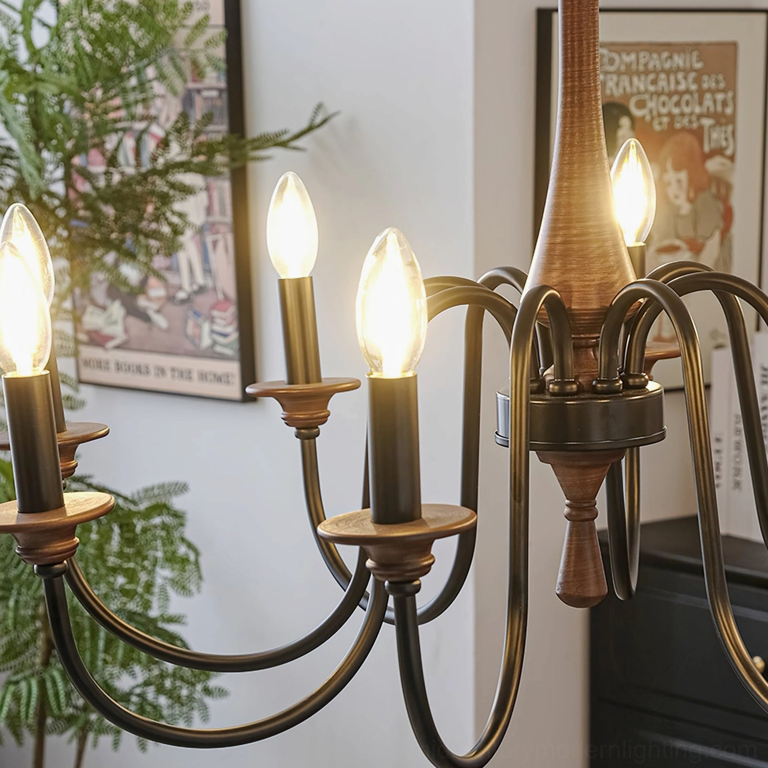 Aubrey chandelier lamp arm close-up showing antique brass socket and glowing warm candle-style bulbs in living room