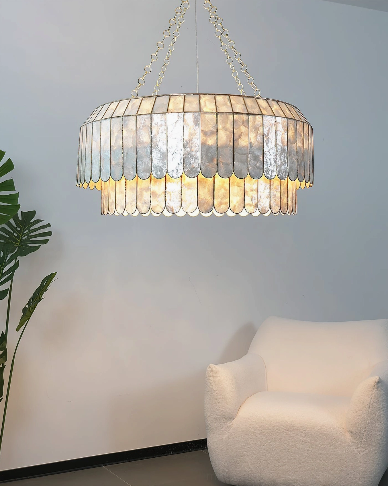 Two-tier capiz chandelier mounted on ceiling showing suspension height and overall sculptural silhouette in modern interior setting