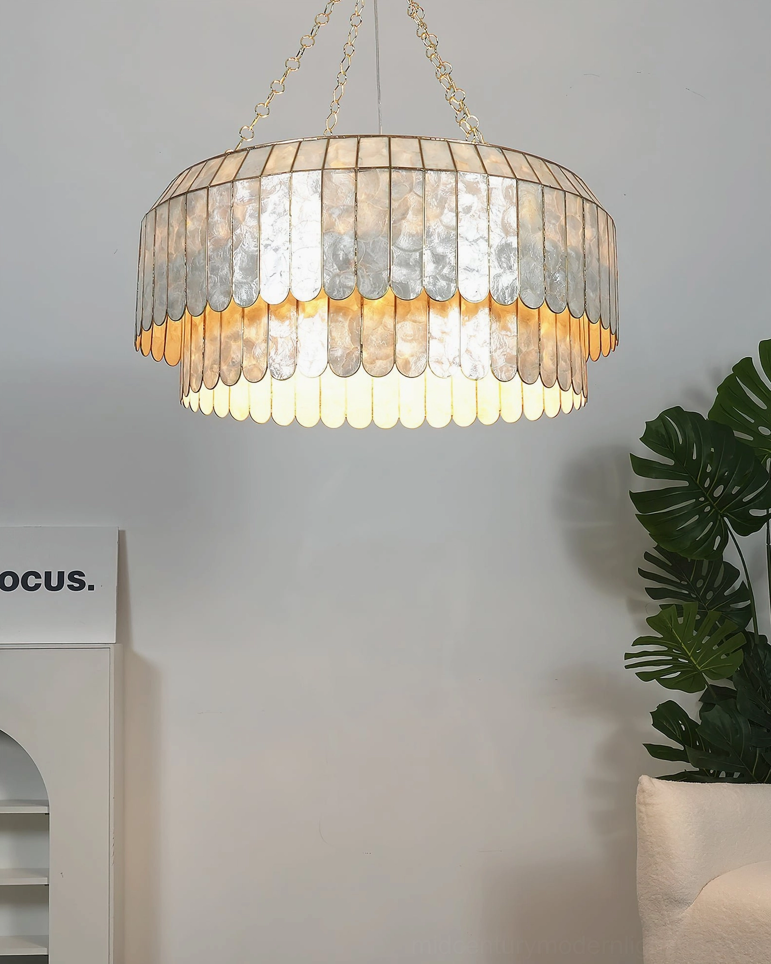 Aurelia capiz pendant hanging in contemporary interior space showing light diffusion through translucent shells, warm ambient glow