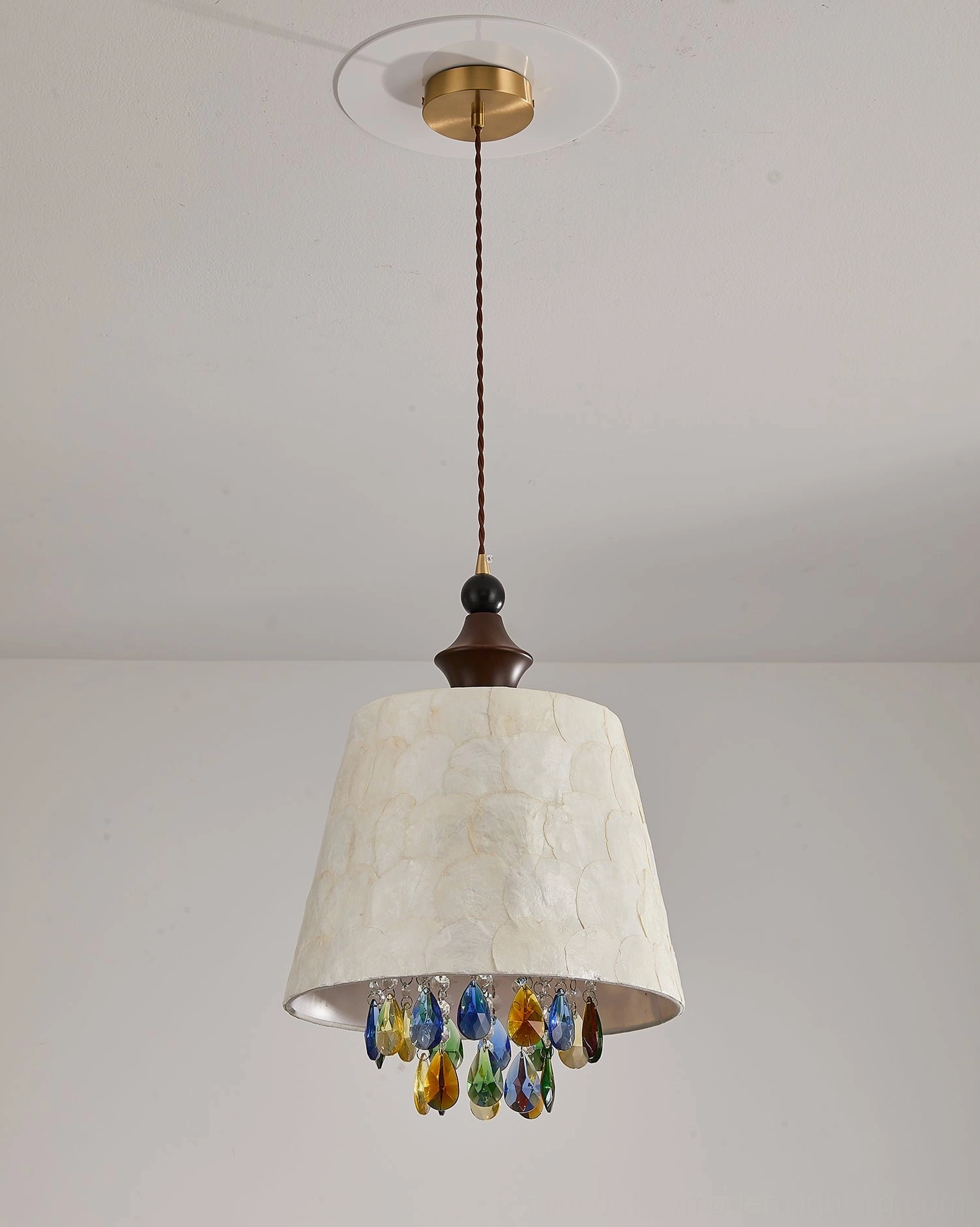 Bottom view of Avery capiz pendant showing brass ceiling mount, brown wooden accent hardware, and mixed-color crystal drops detail