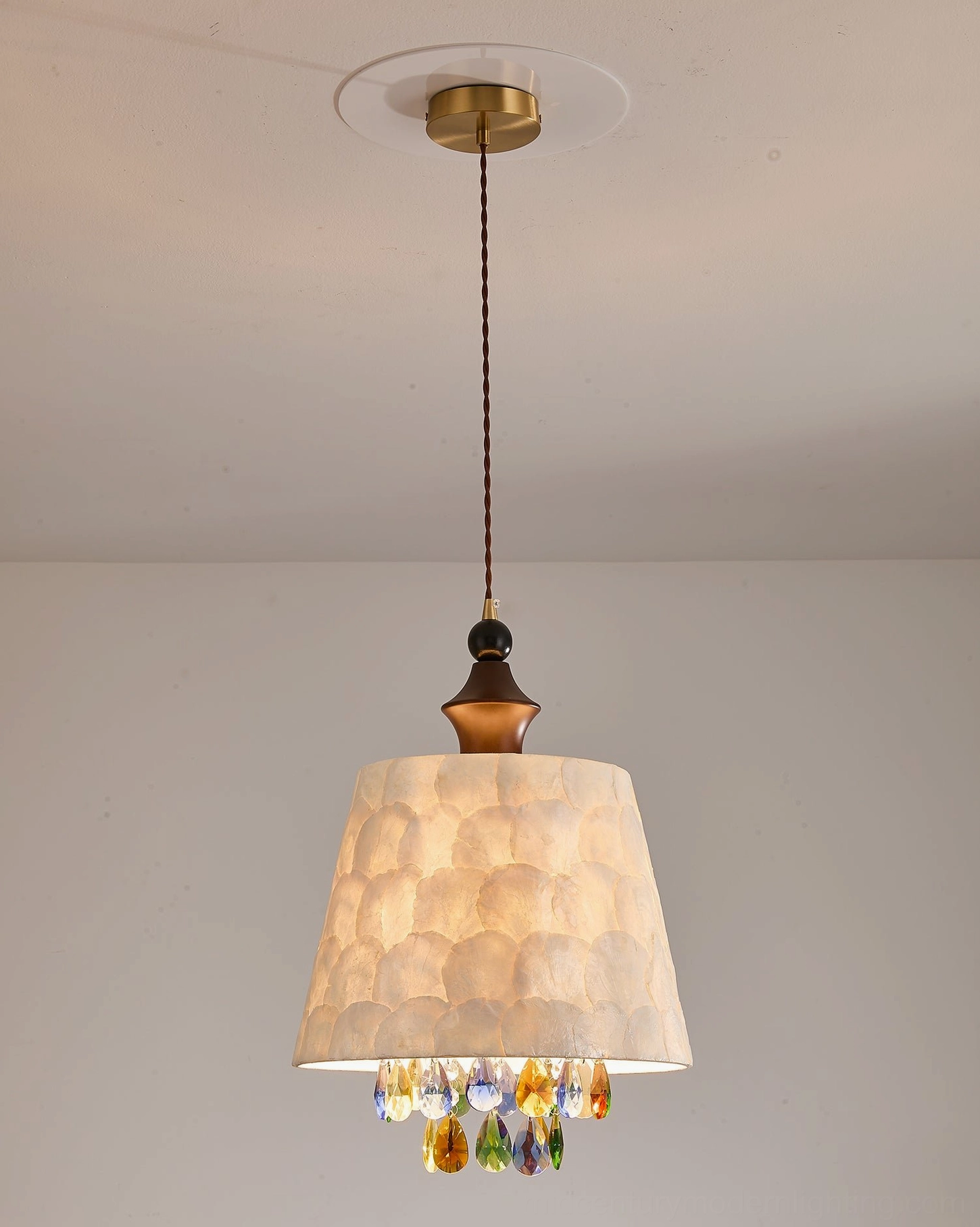 Avery capiz pendant light fixture with brass base and wooden elements in neutral studio lighting showcase