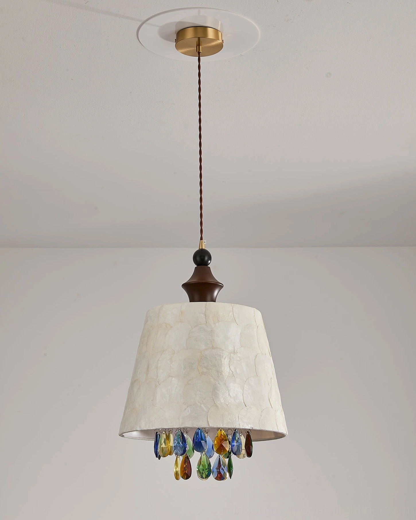 Close-up studio view of Avery capiz shell pendant with dark brown wooden hardware and vivid colored crystal teardrop accents