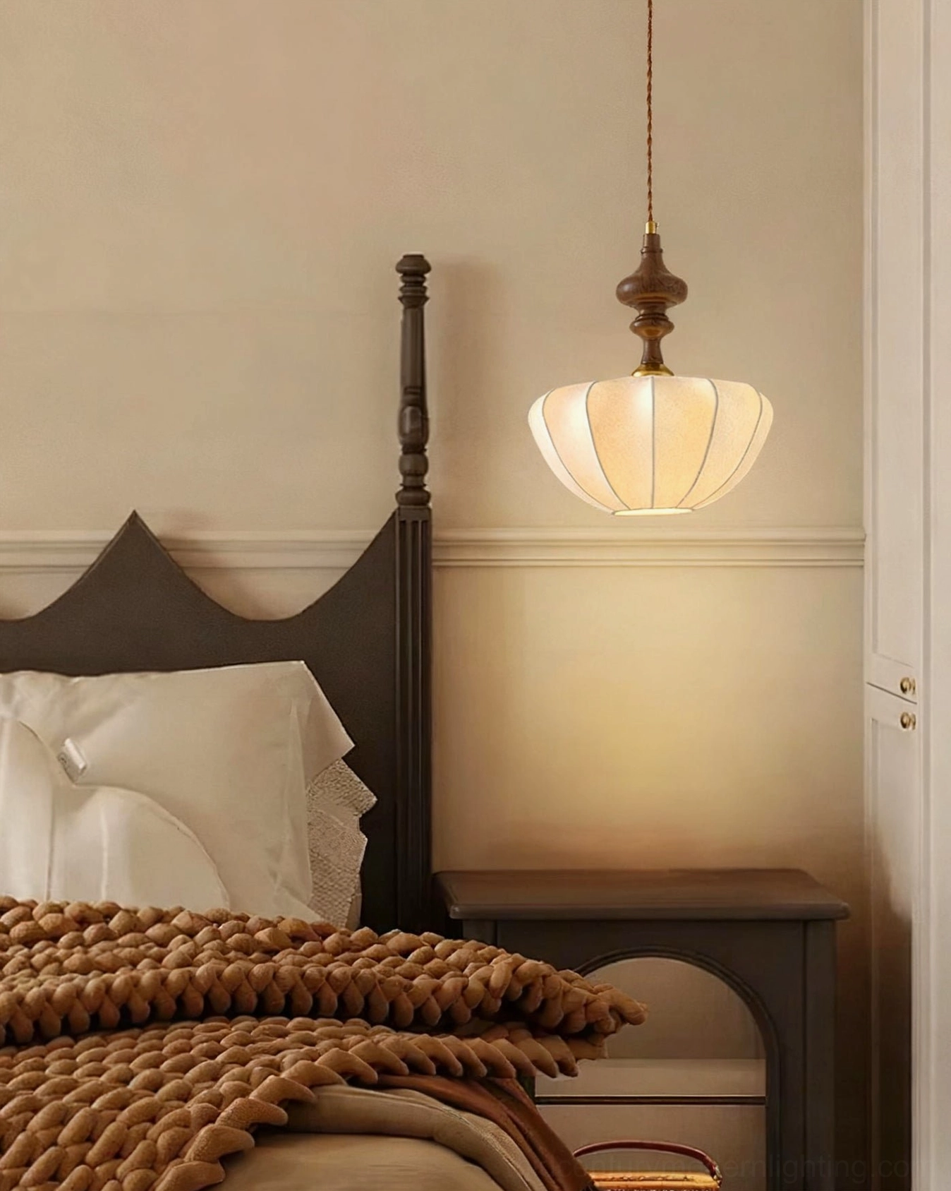 Baird wooden pendant light above dark wood bed with knit throw in cozy cottage-style bedroom