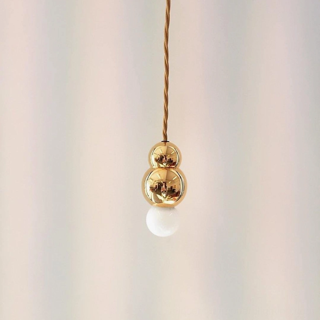 Ball pendant light fixture from below angle, frosted sphere with bulb glow and geometric form highlight