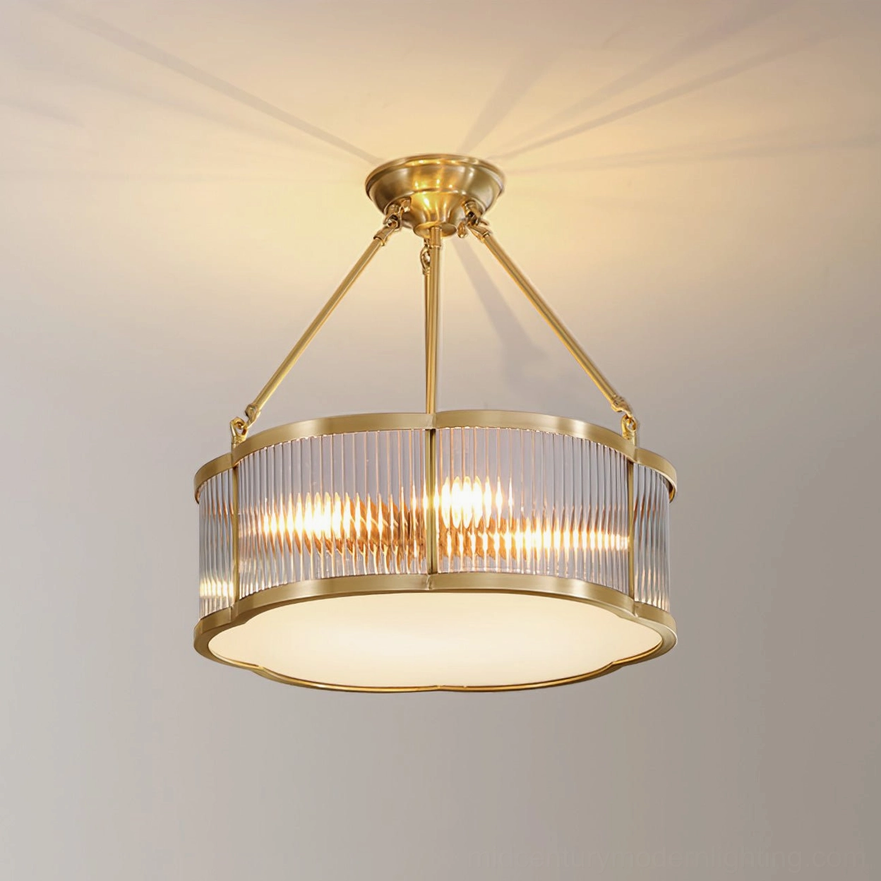 Close-up studio detail shot of polished brass quatrefoil chandelier on beige backdrop showing ribbed glass texture