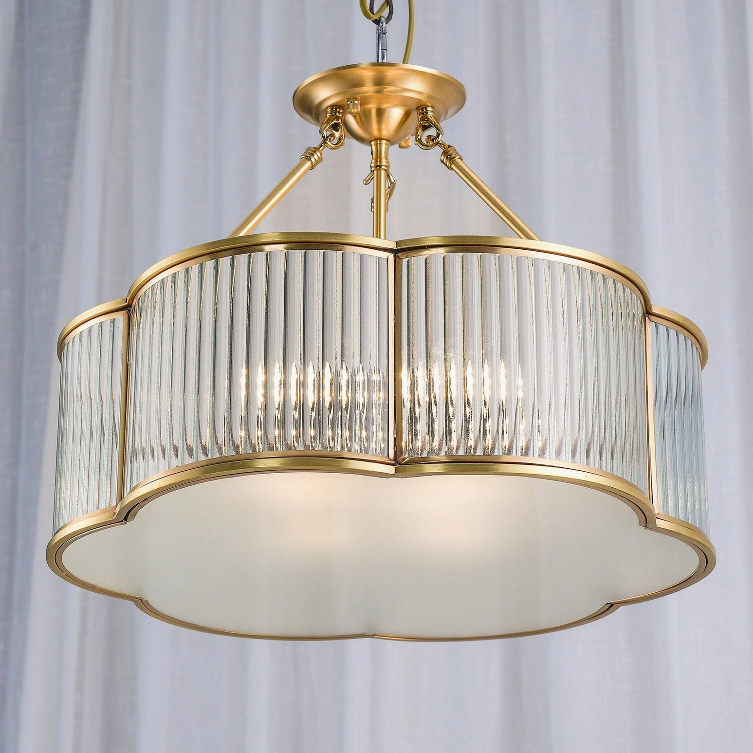 Three-quarter view of polished brass quatrefoil chandelier showing geometric scalloped curves