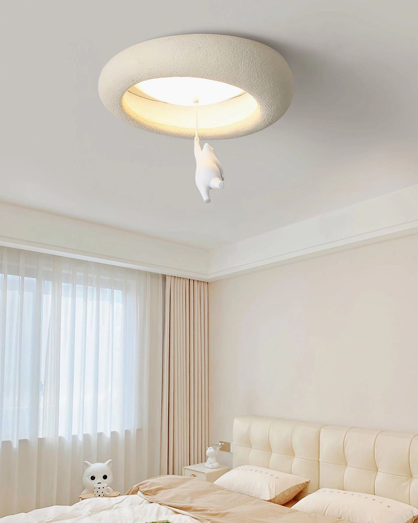 Warm-toned bear ceiling light illuminating bedroom with tufted headboard and soft neutral palette