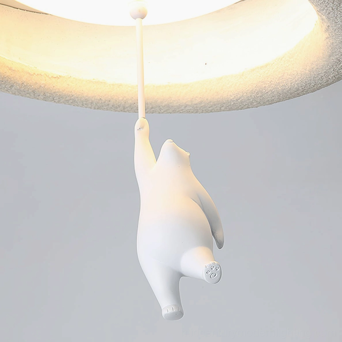 Low-angle close-up of white bear figurine and glowing illuminated rim of modern pendant light