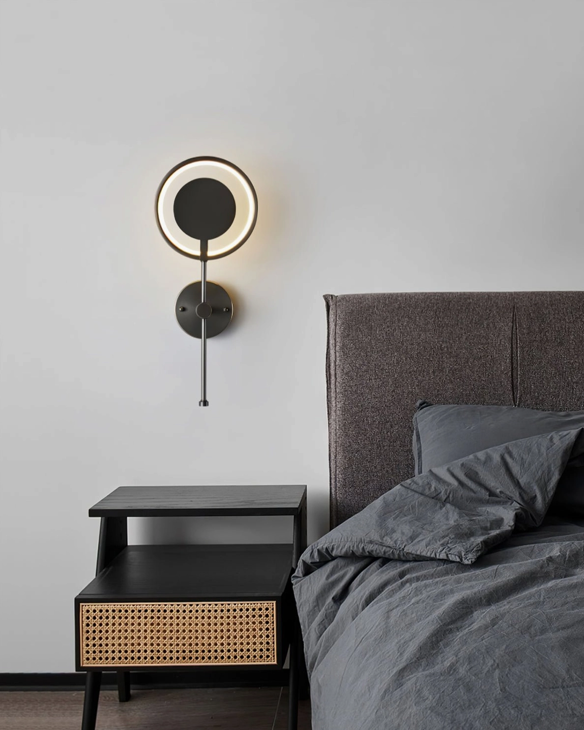 Minimalist bedroom setting with matte black LED ring wall lamp beside bed and bedroom furniture