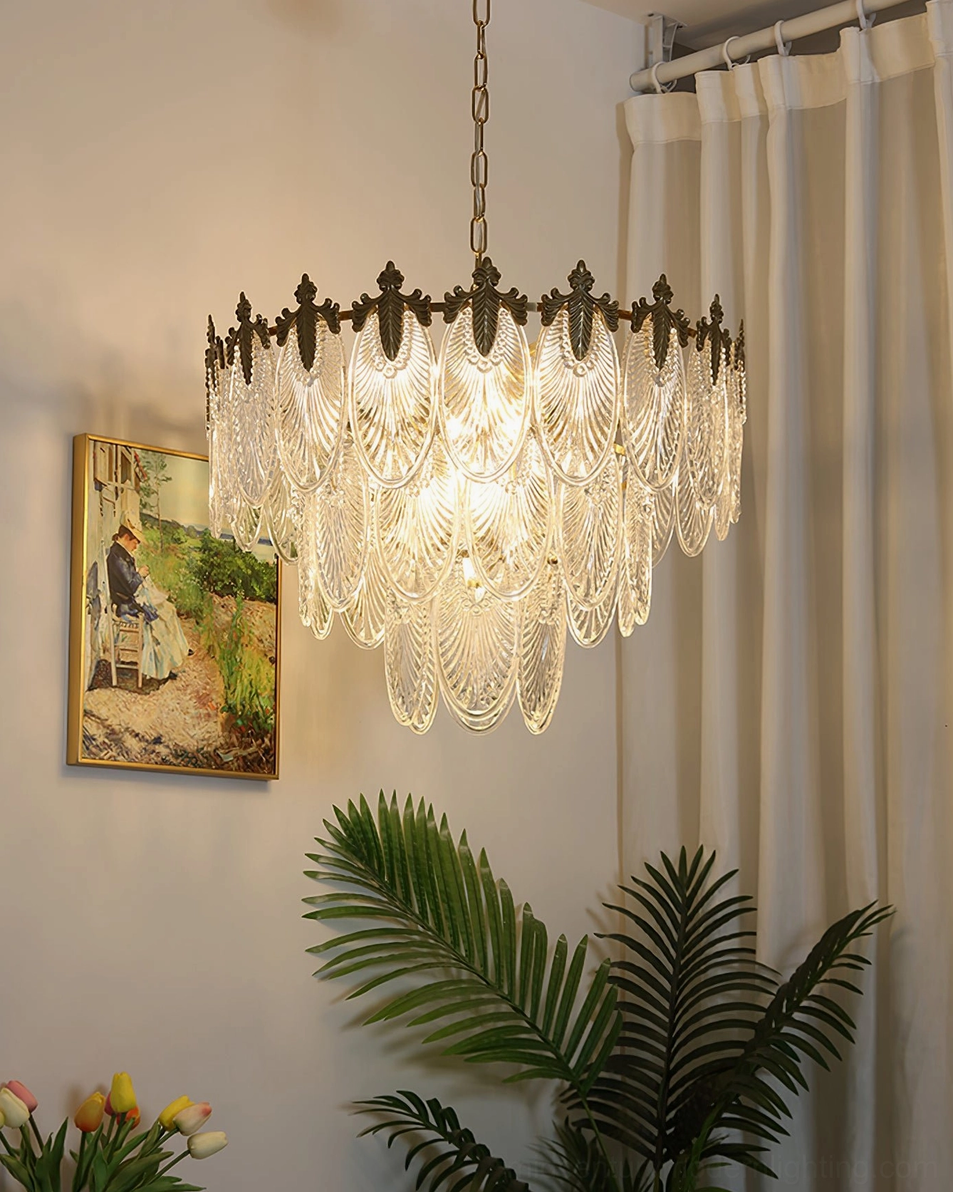 Glowing tiered brass chandelier in bedroom with sheer curtain and palm leaf decor, showing warm diffused light through carved glass