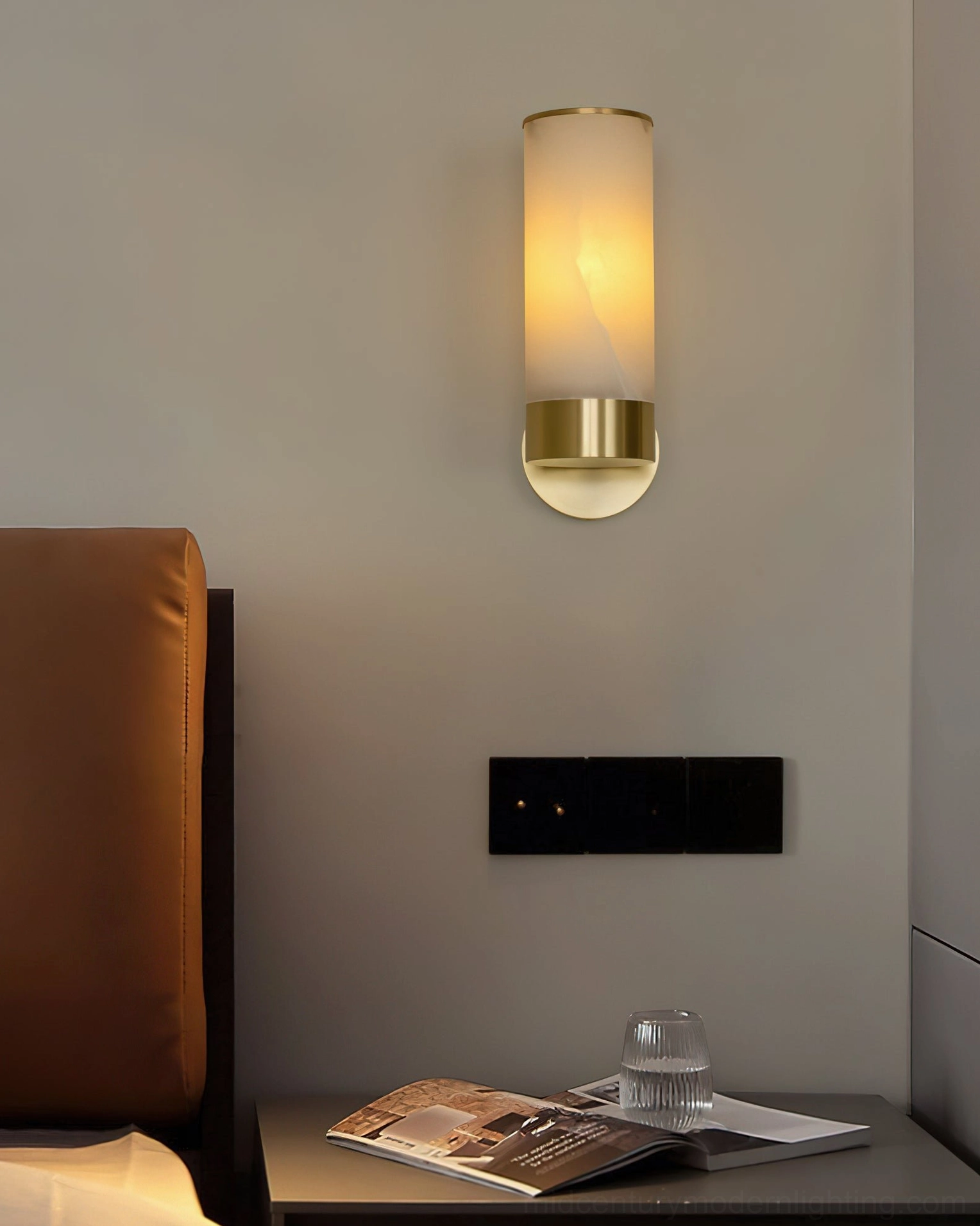 Bedside alabaster wall sconce with brass gold base mounted above nightstand, intimate bedroom accent lighting