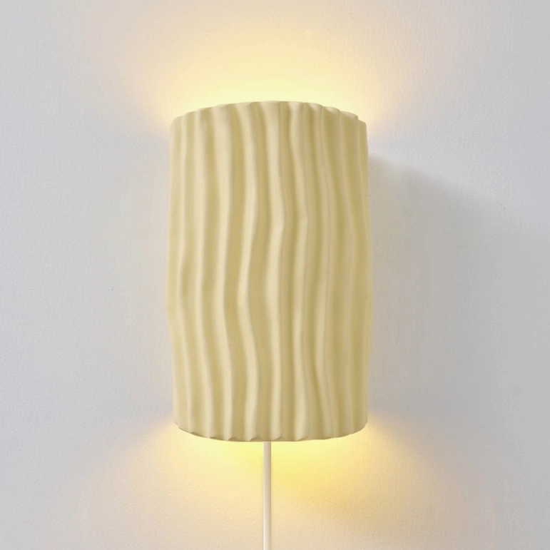 Close-up of beige pleated resin sconce shade with warm G9 LED light, wall-mounted detail shot
