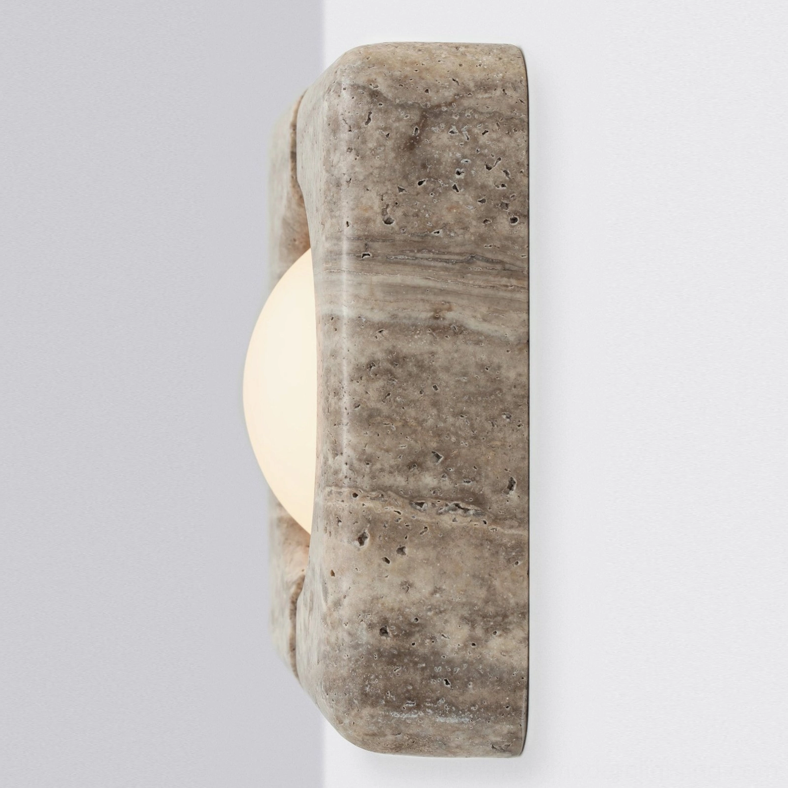 Beige travertine wall lamp front perspective illuminated showing texture and light diffusion