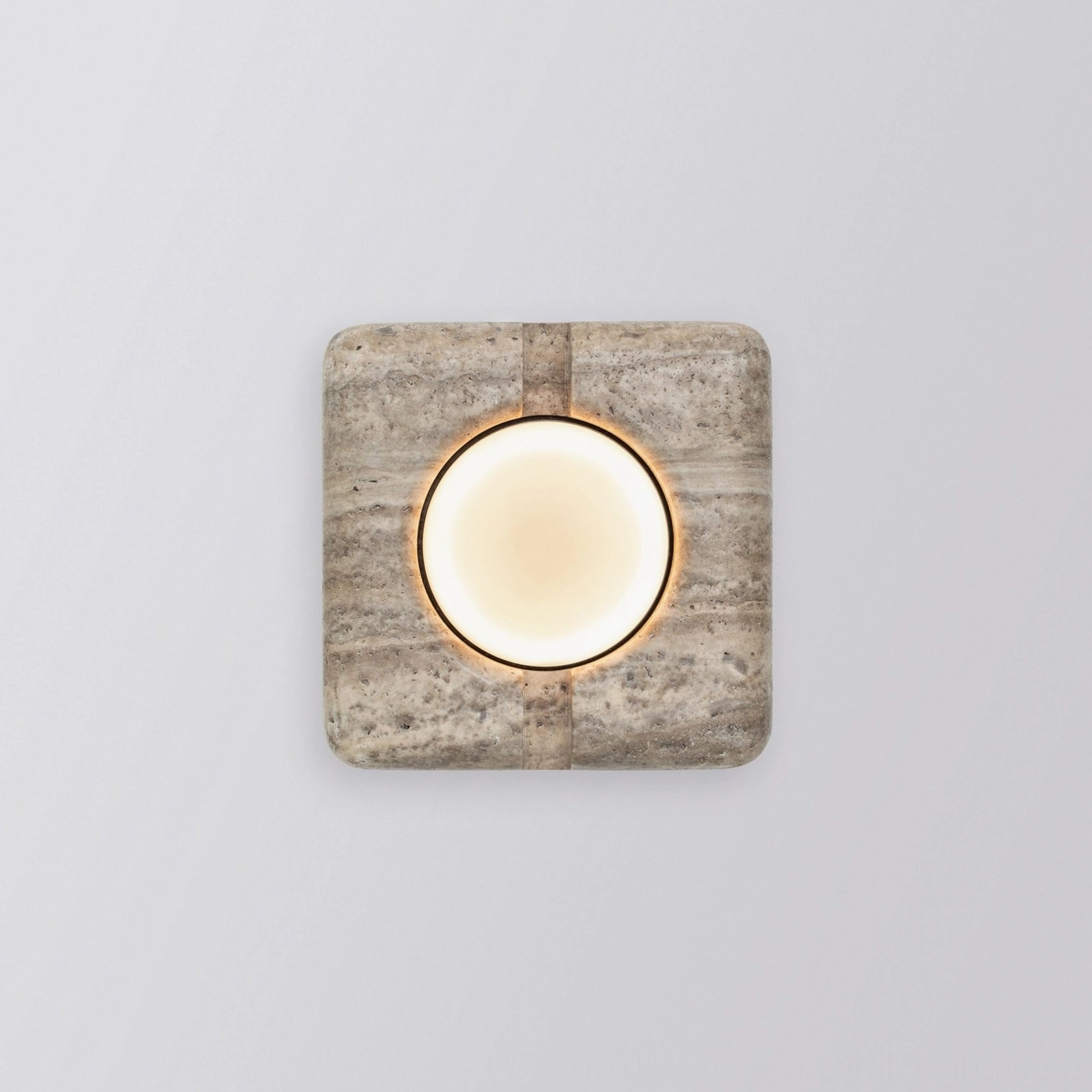 Front view of beige travertine wall lamp fully illuminated with continuous warm light