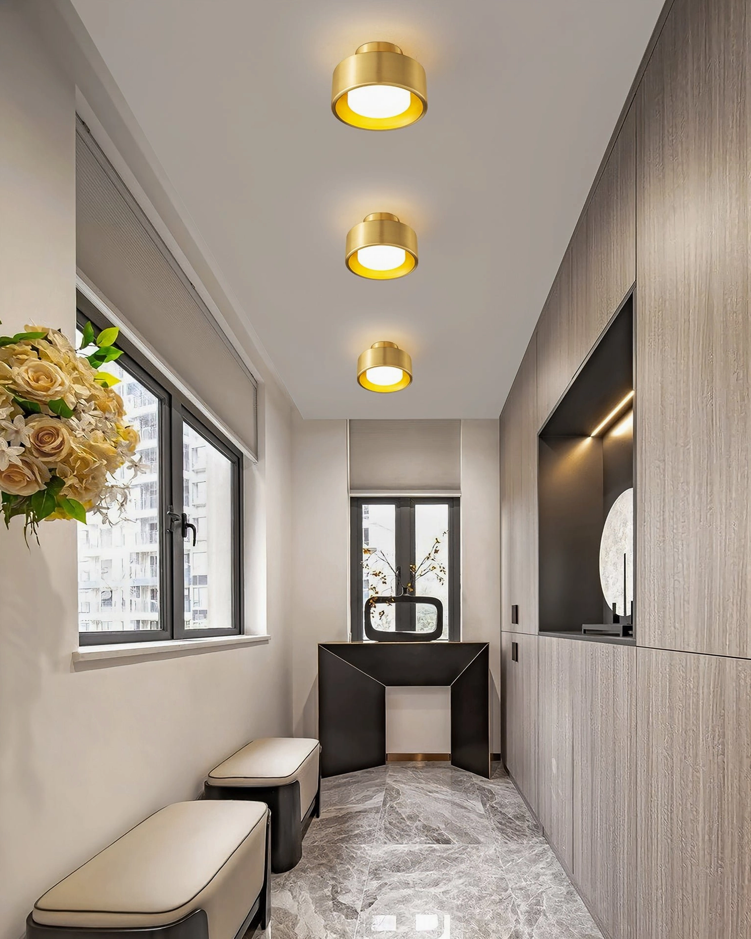 Three brass Bella ceiling lamps installed in residential hallway corridor with wood cladding showing warm brass finish