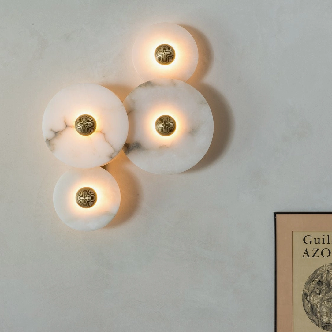 Close-up detail of Beran alabaster wall lamp showing veined stone texture, warm LED illumination, and sculptural alabaster disc shapes on accent wall